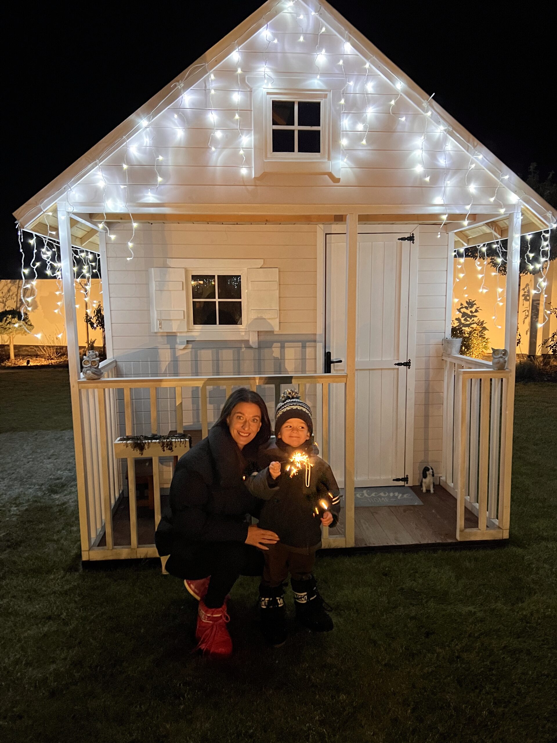 šťastná mama so svojím synom pri záhradnom domčeku pre deti